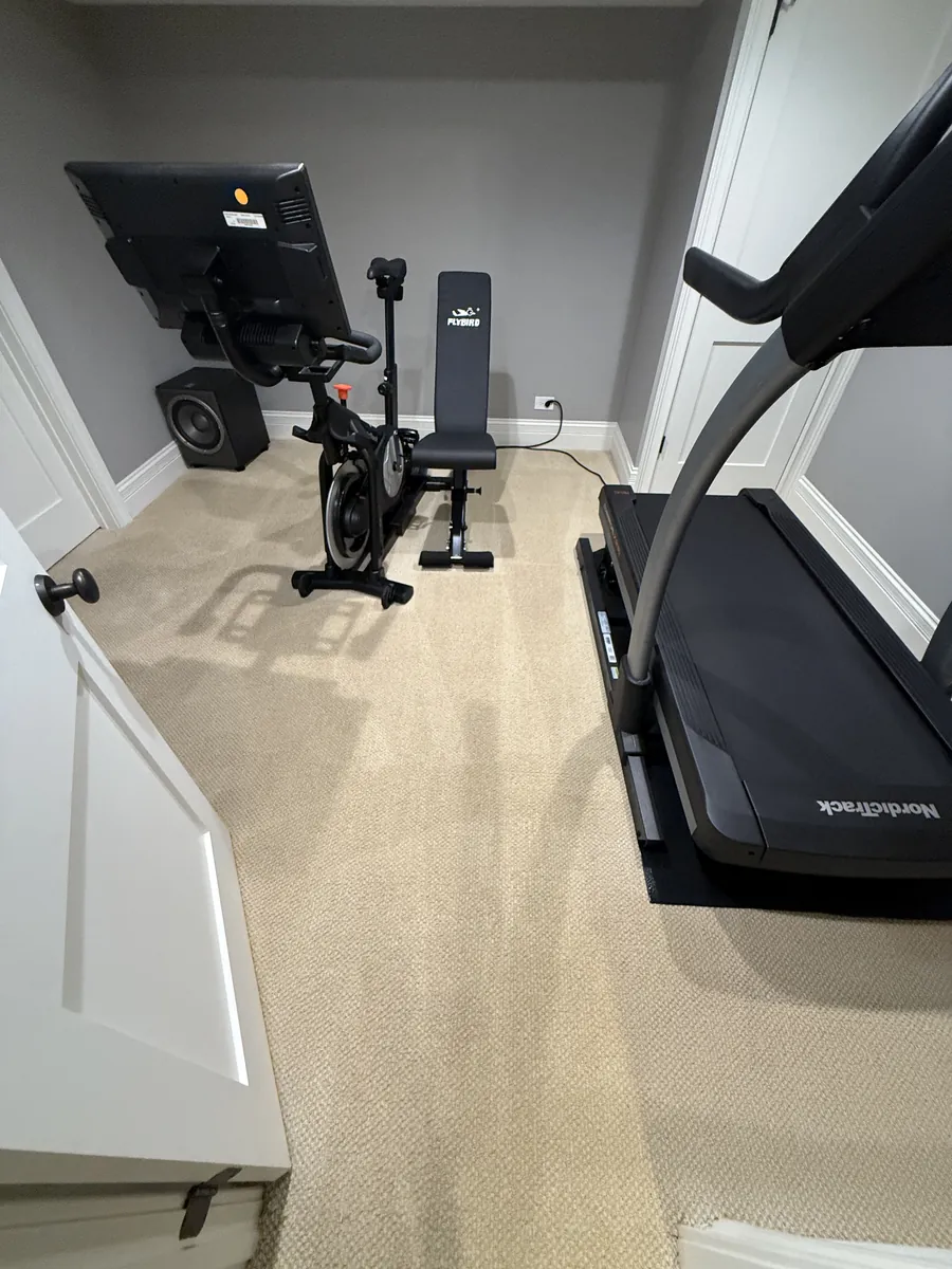 Home gym room in a Glenview basement with freshly cleaned beige loop carpet around a treadmill and exercise bike
