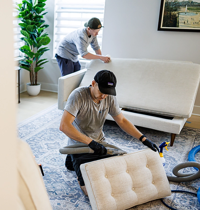 two men cleaning couch